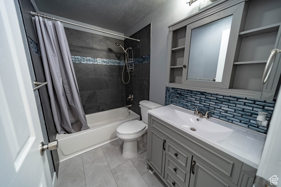 Full bath featuring shower / bathtub combination with curtain, decorative backsplash, a textured ceiling, vanity, and tile patterned flooring
