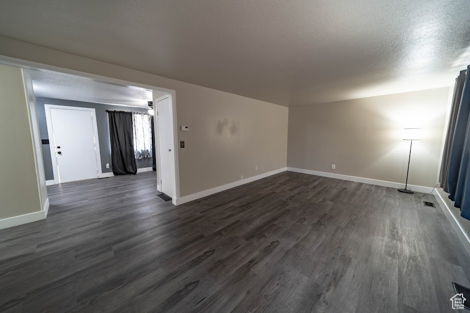 Unfurnished room featuring dark wood-style flooring and a textured ceiling