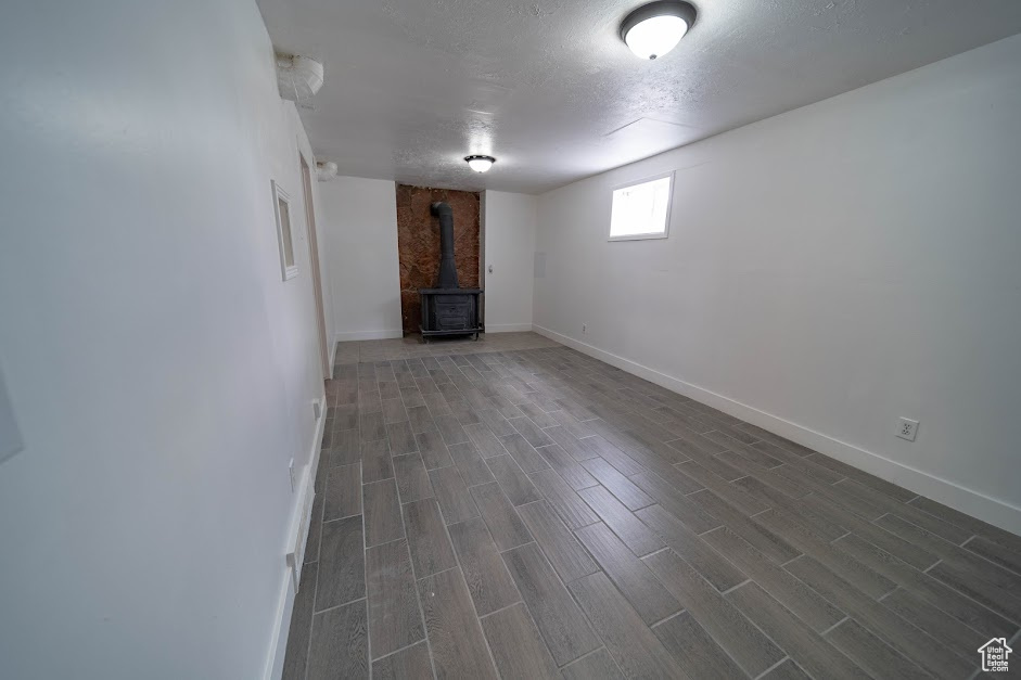 Below grade area with a wood stove, dark wood finished floors, and a textured ceiling