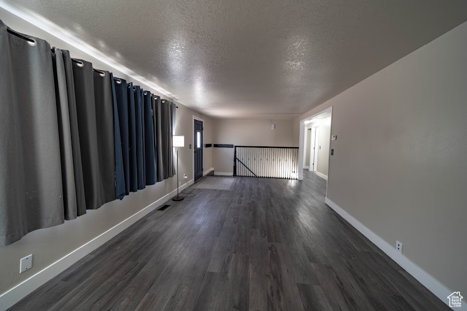 Unfurnished room with a textured ceiling and dark wood finished floors