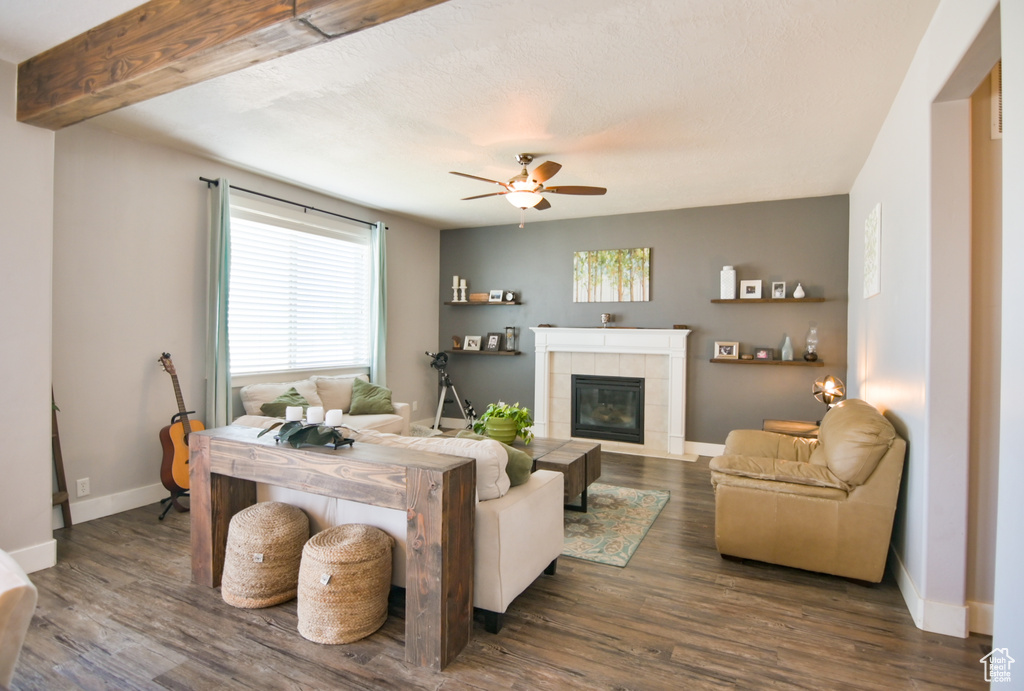 Living room with a ceiling fan, healthy amount of natural light, a tile fireplace, and dark wood-style flooring