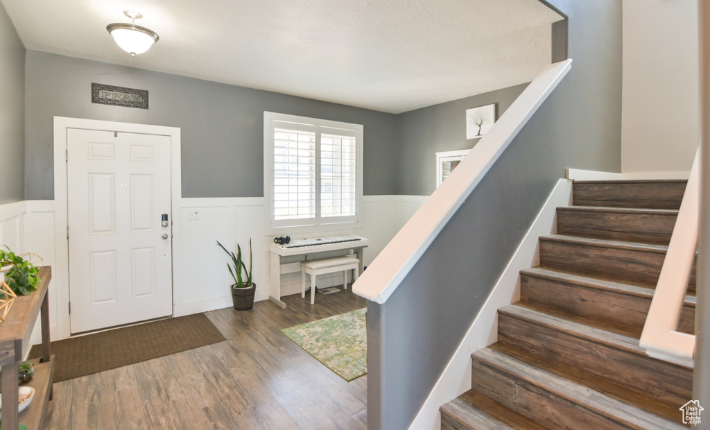 Foyer with wood finished floors, a wainscoted wall, and stairway