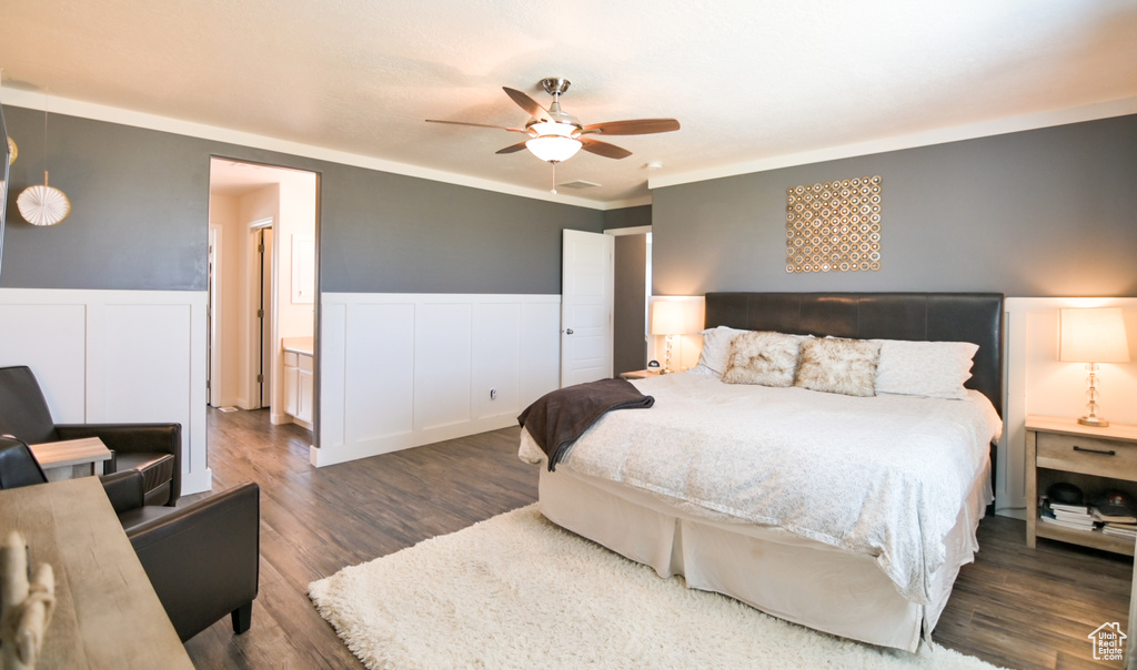 Bedroom with wainscoting, wood finished floors, ornamental molding, a decorative wall, and ceiling fan