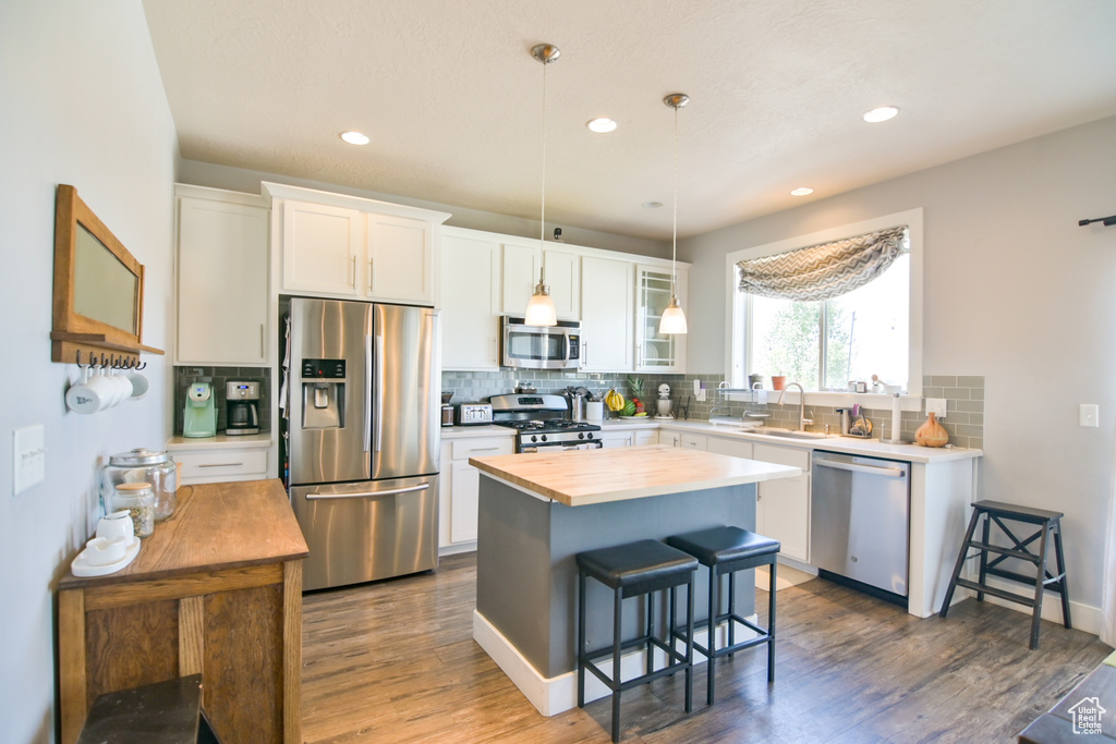 Kitchen featuring stainless steel appliances, wood counters, a breakfast bar, white cabinets, and recessed lighting