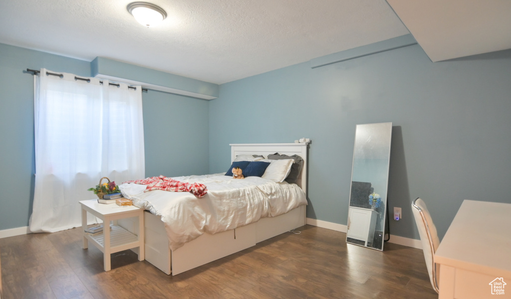 Bedroom with dark wood-style flooring and a textured ceiling