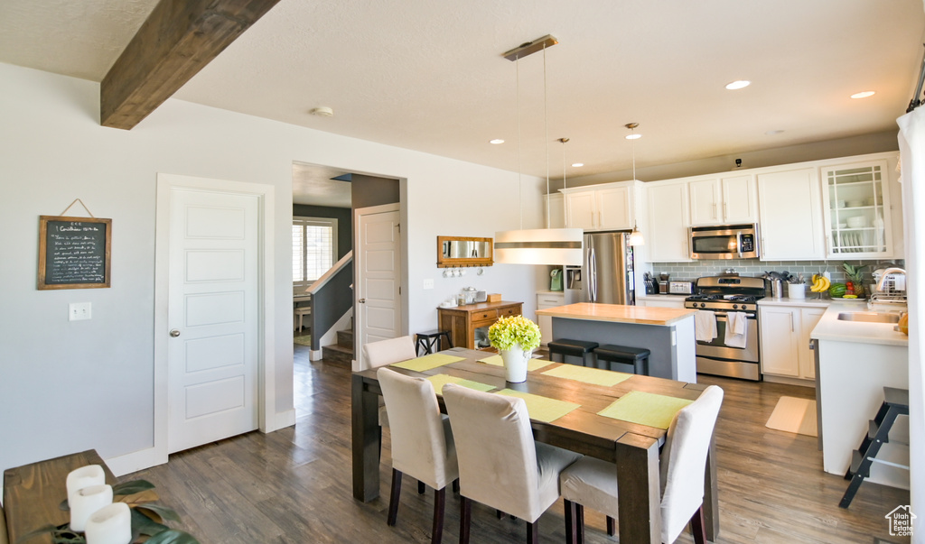 Dining area with dark wood finished floors, beamed ceiling, recessed lighting, and stairs