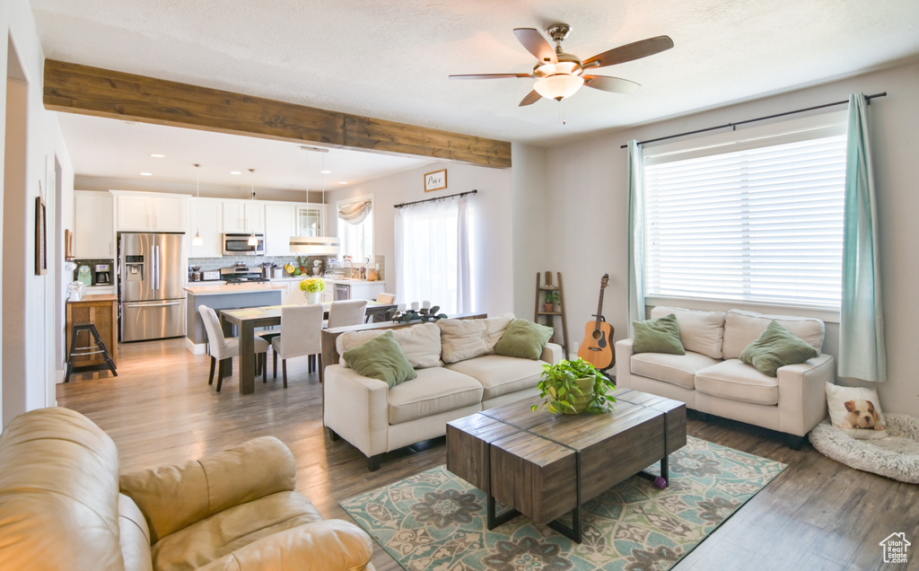 Living area featuring a ceiling fan, wood finished floors, beam ceiling, and recessed lighting