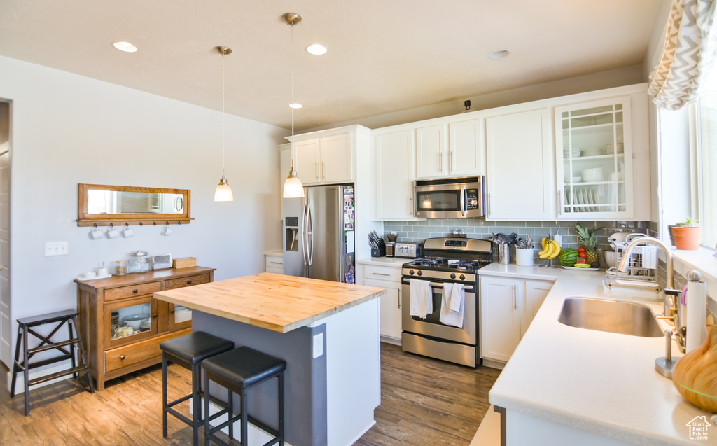 Kitchen featuring stainless steel appliances, a breakfast bar, butcher block countertops, wood finished floors, and recessed lighting