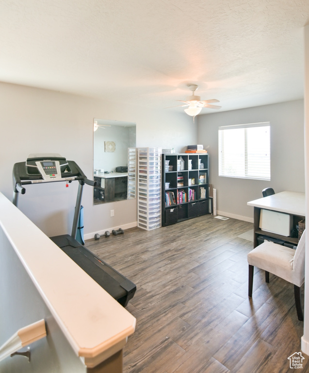 Workout area with a ceiling fan and wood finished floors