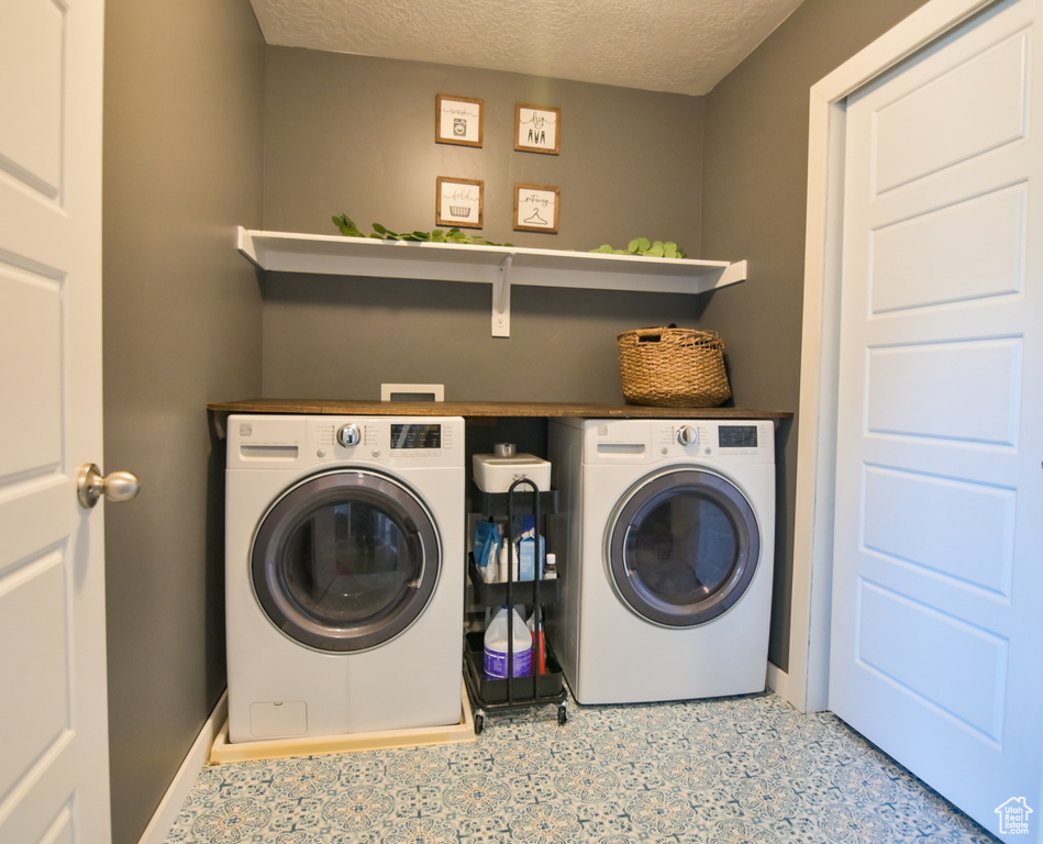 Laundry room with washing machine and dryer and a textured ceiling