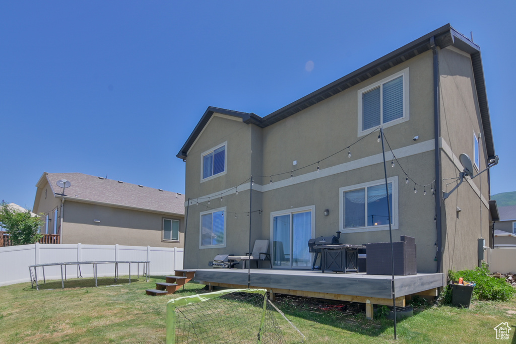 Back of house featuring a wooden deck and stucco siding