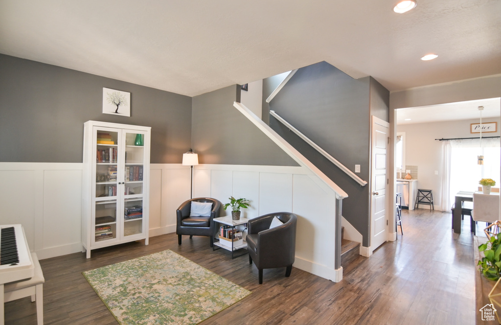 Living area featuring stairway, recessed lighting, dark wood finished floors, wainscoting, and a decorative wall