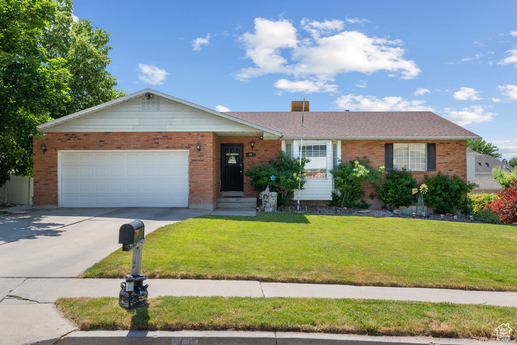 Ranch-style house with brick siding, concrete driveway, a front lawn, and an attached garage