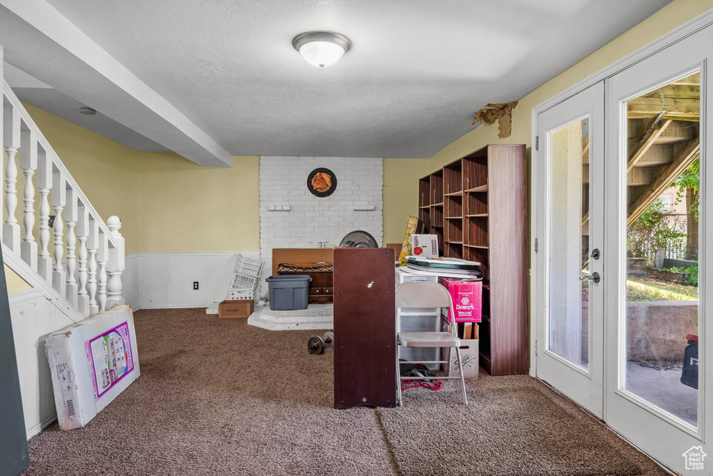 Carpeted office with a wainscoted wall, a fireplace, and a textured ceiling
