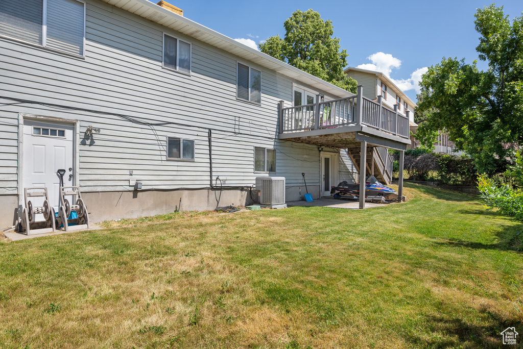 Rear view of house with a wooden deck, a lawn, and a patio