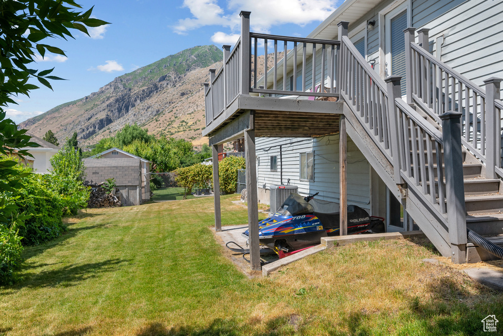 View of grassy yard featuring stairway and a deck with mountain view