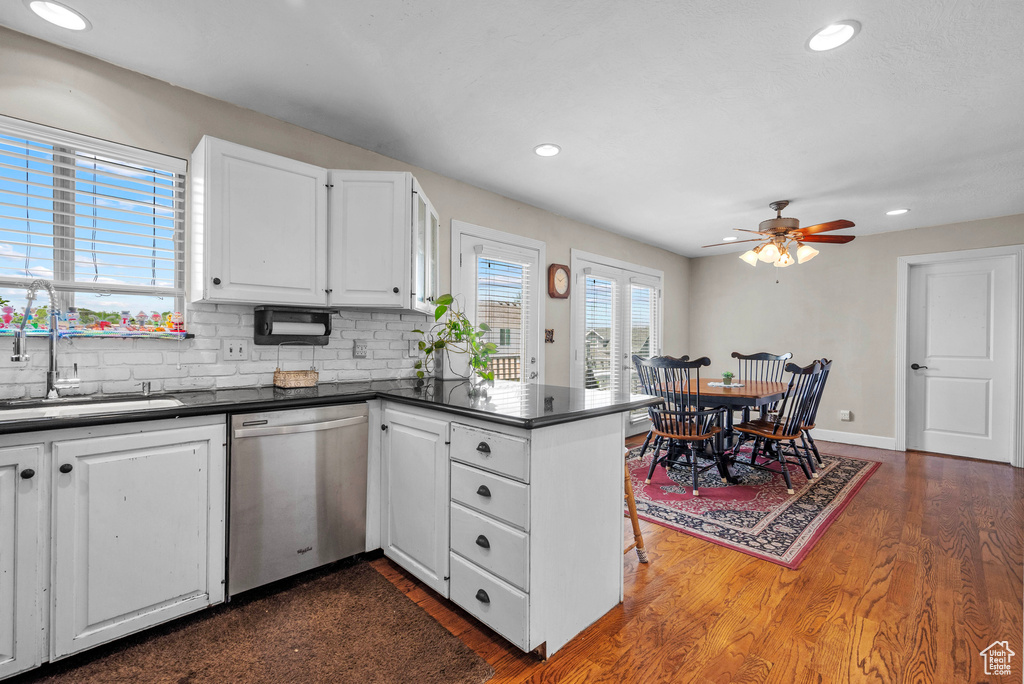 Kitchen with dishwasher, dark countertops, dark wood-style floors, a peninsula, and recessed lighting