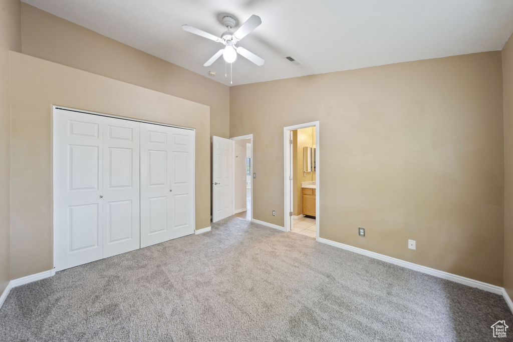 Unfurnished bedroom featuring light colored carpet, a closet, lofted ceiling, ceiling fan, and ensuite bathroom