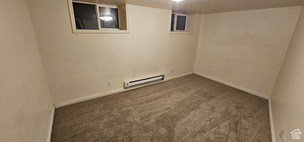 Carpeted spare room featuring a baseboard heating unit and baseboards