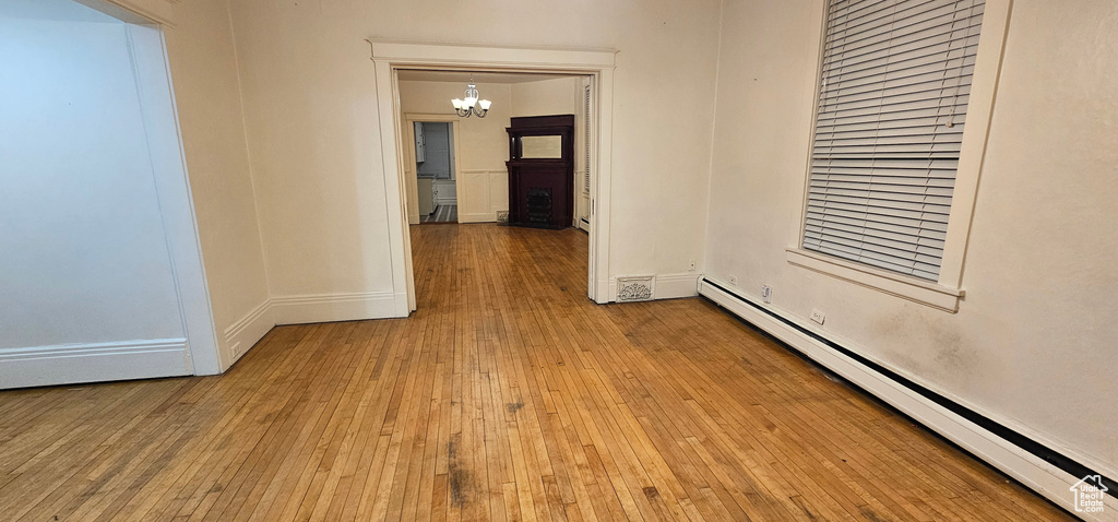 Spare room with baseboard heating, a chandelier, and hardwood / wood-style flooring