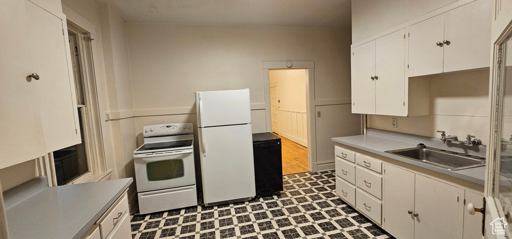 Kitchen with white appliances, dark flooring, light countertops, and white cabinetry