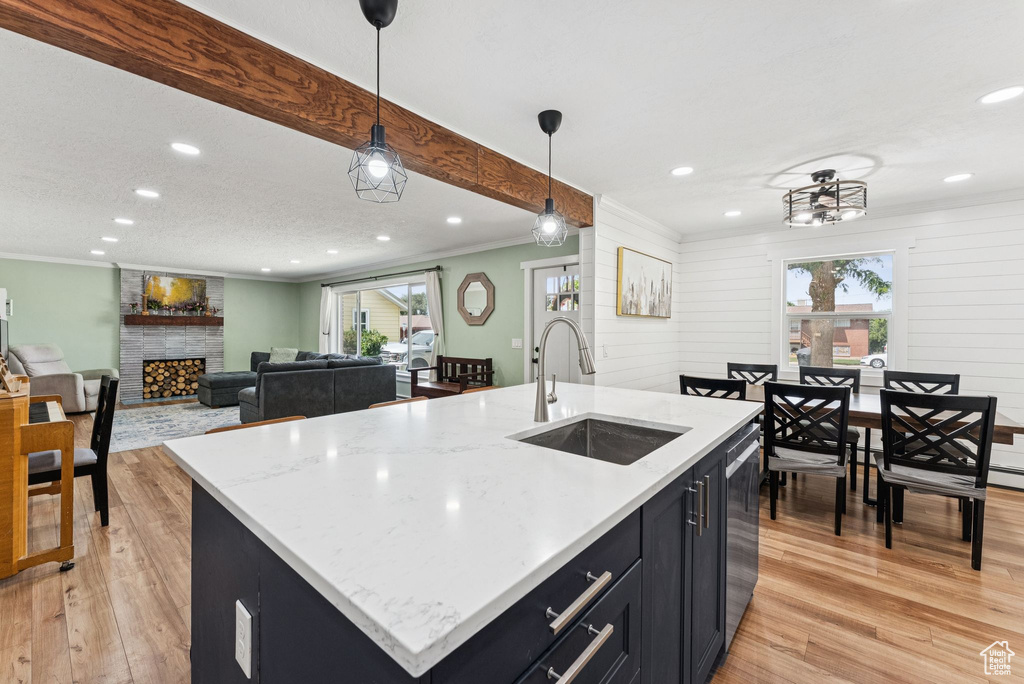 Kitchen featuring plenty of natural light, dark cabinets, light wood-style floors, recessed lighting, and hanging light fixtures