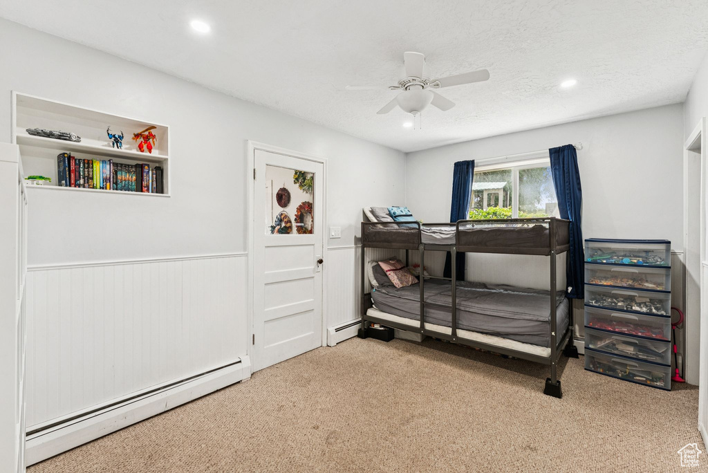 Carpeted bedroom with a baseboard heating unit, recessed lighting, a wainscoted wall, and ceiling fan