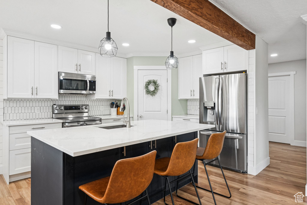 Kitchen featuring stainless steel appliances, tasteful backsplash, recessed lighting, a kitchen breakfast bar, and white cabinetry