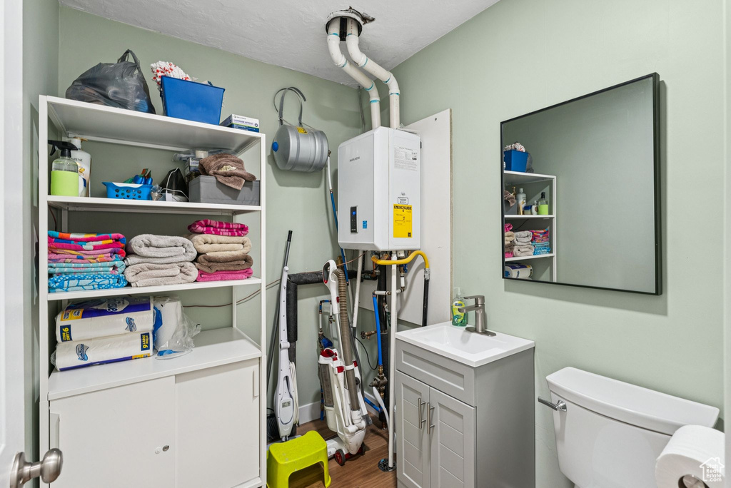 Utilities featuring tankless water heater and a sink