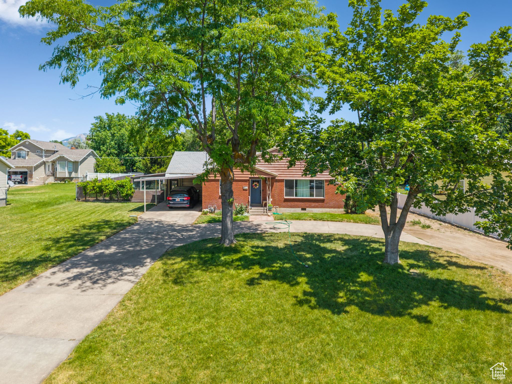 View of front of house with driveway, brick siding, an attached carport, and a front yard
