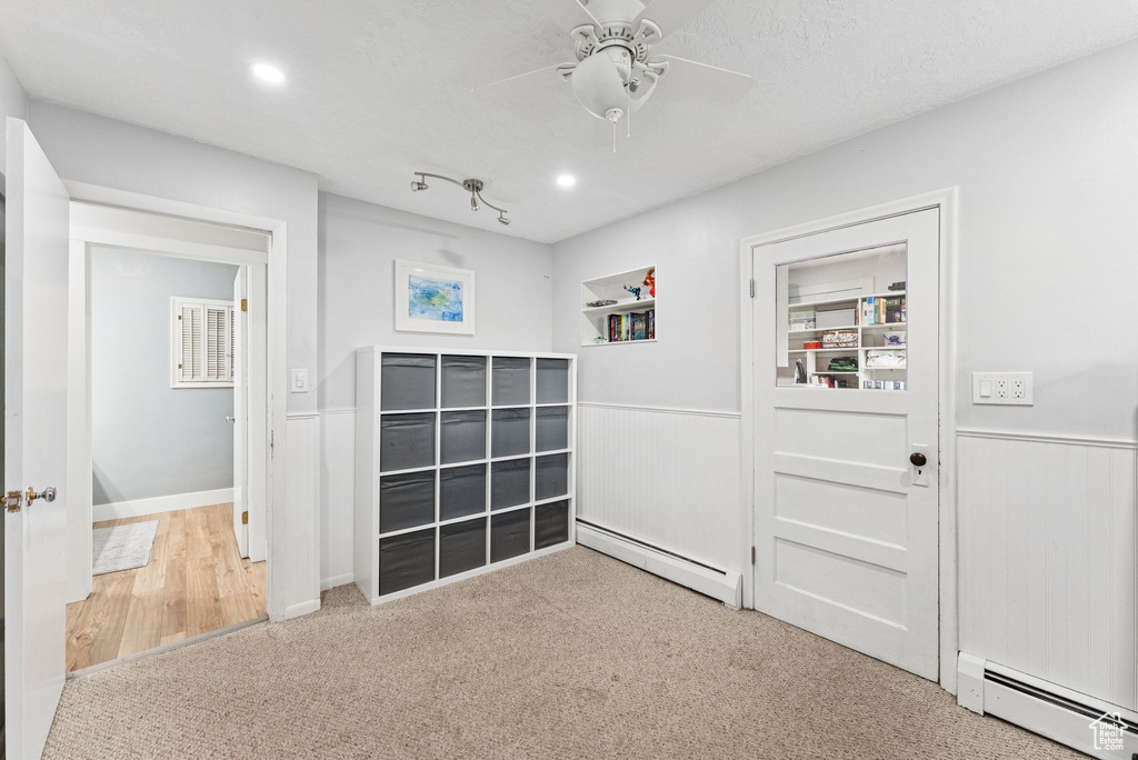 Hallway featuring a baseboard radiator, carpet, wainscoting, and recessed lighting