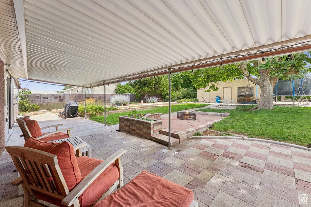Fenced backyard with a trampoline, a patio, and an outbuilding