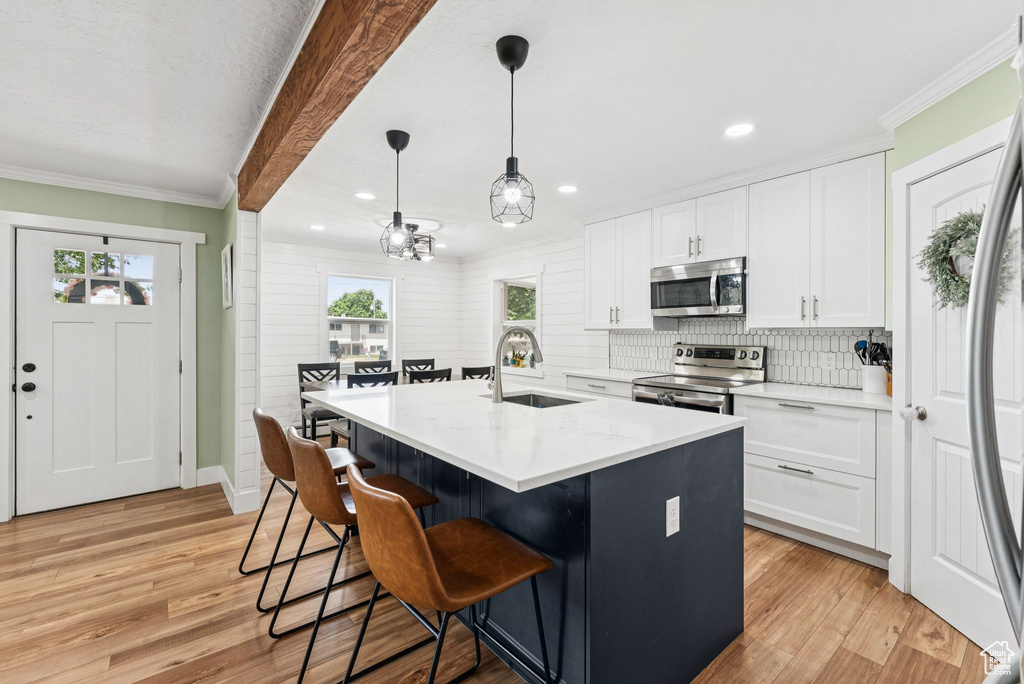 Kitchen featuring stainless steel appliances, light wood-style flooring, white cabinetry, backsplash, and recessed lighting