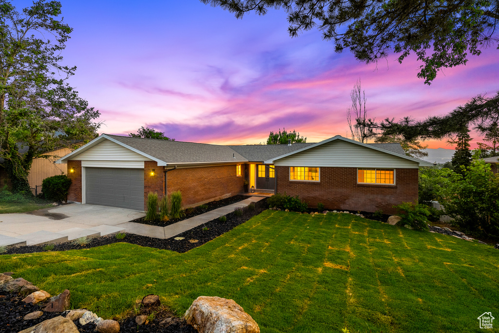 Ranch-style home with brick siding, concrete driveway, a garage, and a lawn