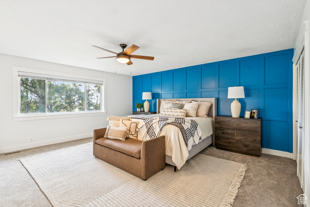 Bedroom with carpet, a decorative wall, and a ceiling fan