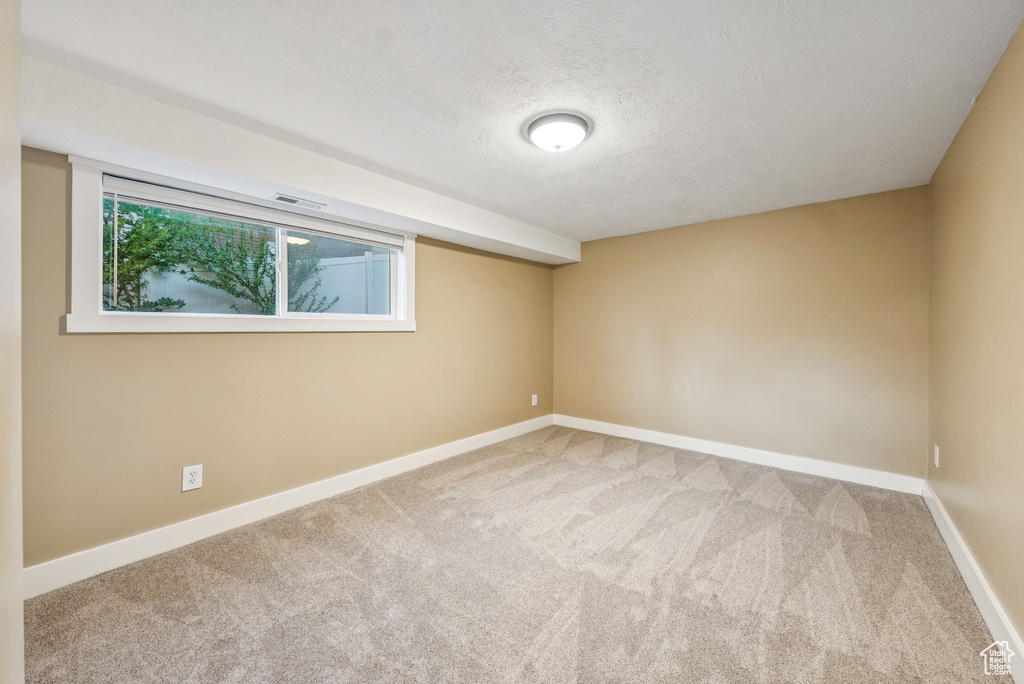 Spare room featuring carpet floors, healthy amount of natural light, and a textured ceiling