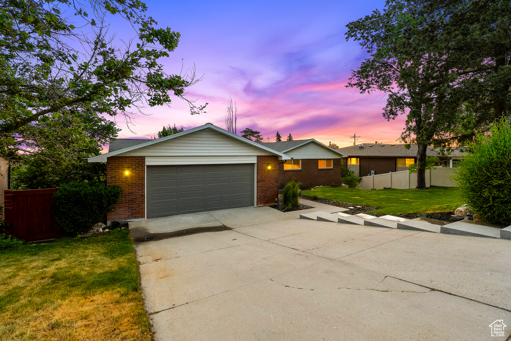 Ranch-style home featuring brick siding, an attached garage, and driveway