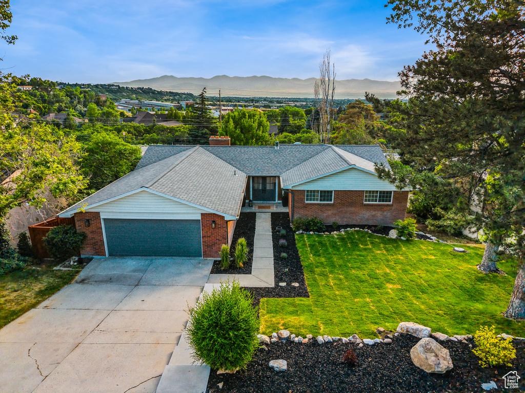 Single story home with brick siding, a front lawn, concrete driveway, a garage, and a mountain view