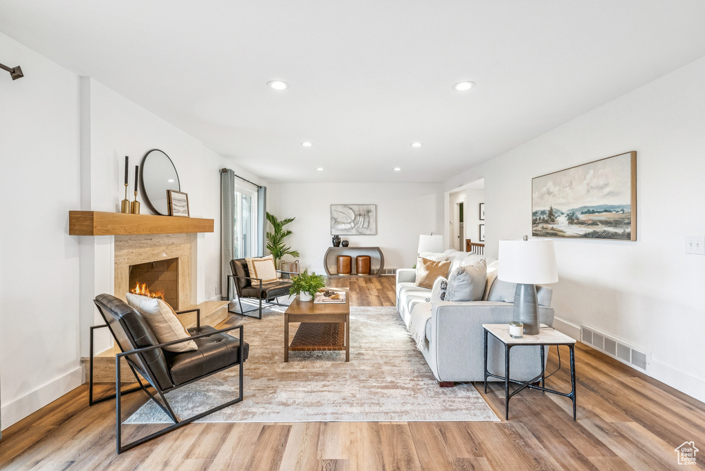 Living room with wood finished floors, recessed lighting, and a lit fireplace