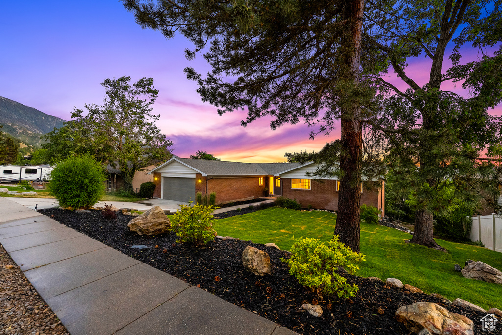 View of front of house with brick siding, an attached garage, concrete driveway, and a mountain view