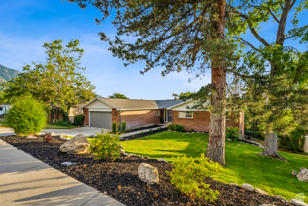 Single story home with brick siding, a garage, a front yard, and concrete driveway