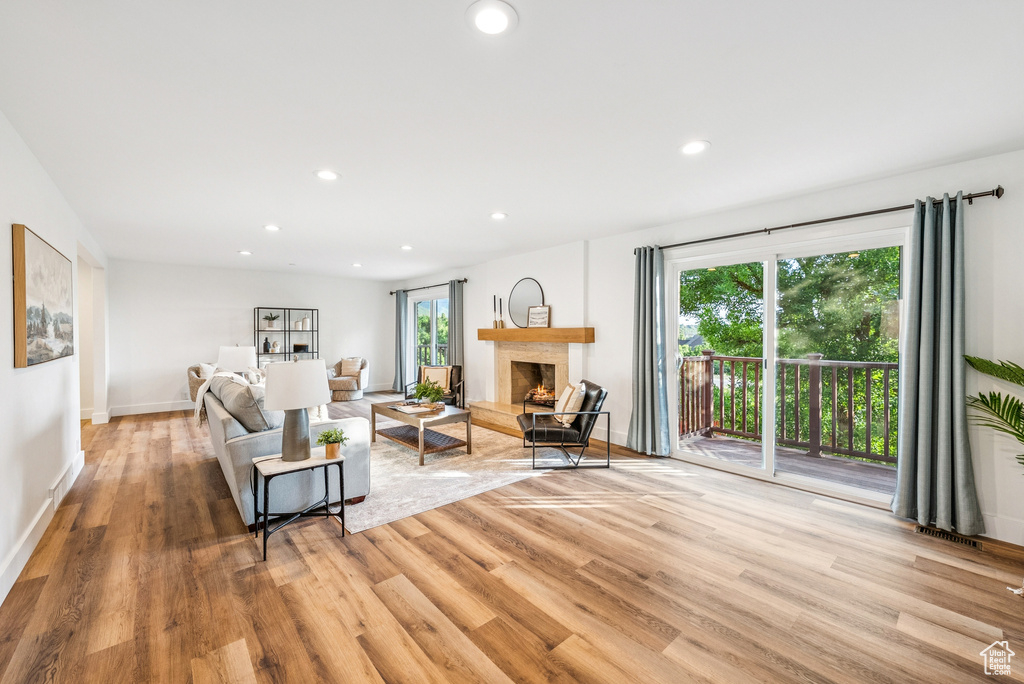 Living area with light wood finished floors, recessed lighting, and a warm lit fireplace