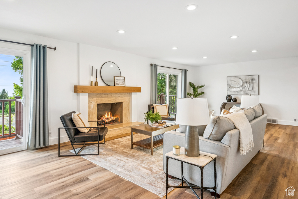 Living room with wood finished floors, a high end fireplace, and recessed lighting