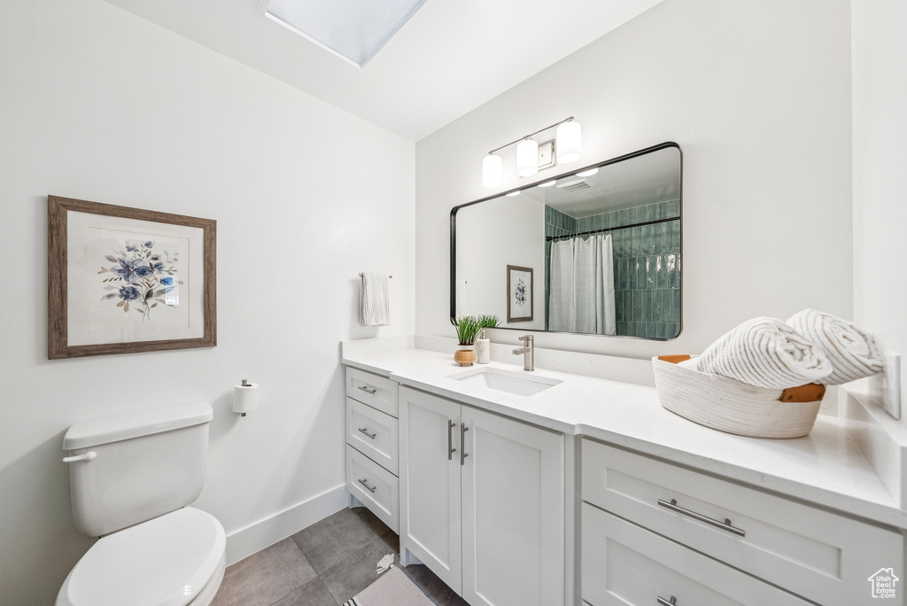 Full bath featuring vanity, tile patterned flooring, a skylight, and a shower with shower curtain