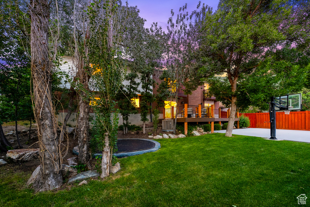 Yard at dusk featuring a trampoline and a deck