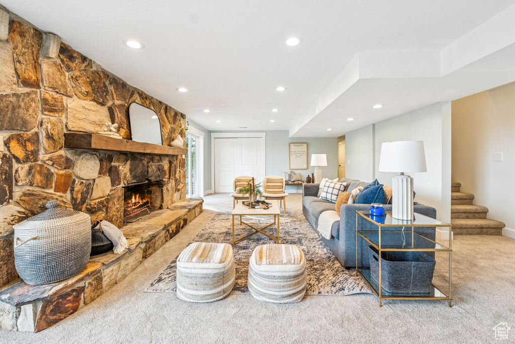 Living room with carpet floors, recessed lighting, a stone fireplace, and stairs