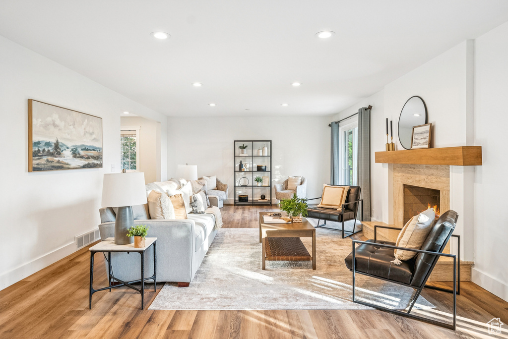 Living room featuring plenty of natural light, light wood finished floors, recessed lighting, and a high end fireplace
