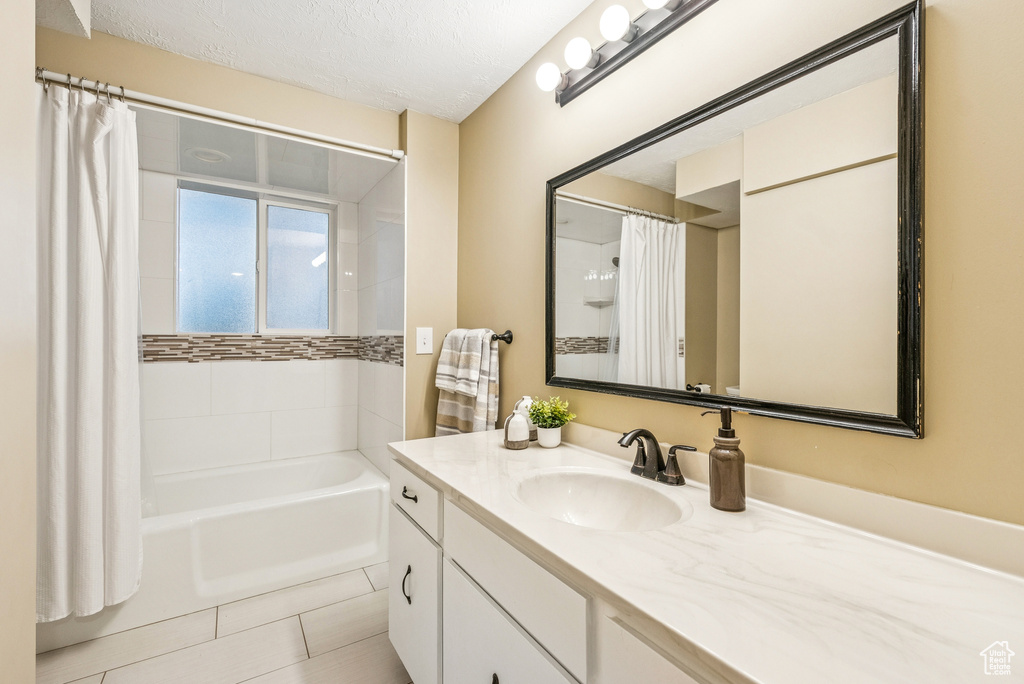 Full bathroom featuring vanity, tile patterned floors, shower / tub combo, and a textured ceiling