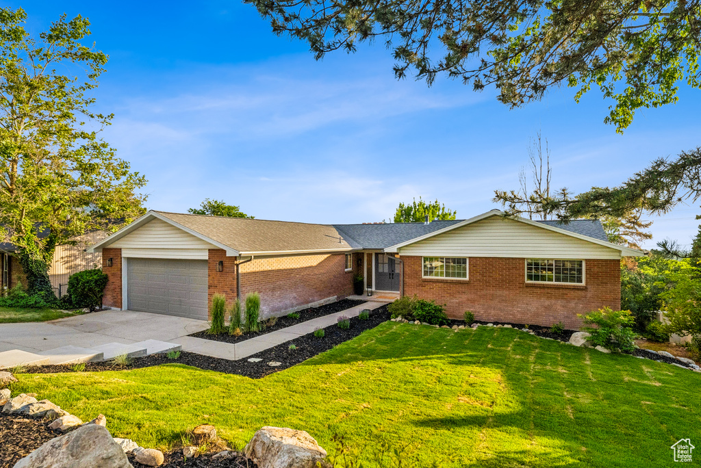 Single story home featuring brick siding, concrete driveway, a front lawn, and an attached garage