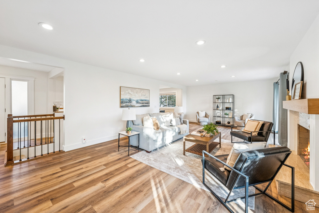 Living room with light wood-style floors, a high end fireplace, and recessed lighting